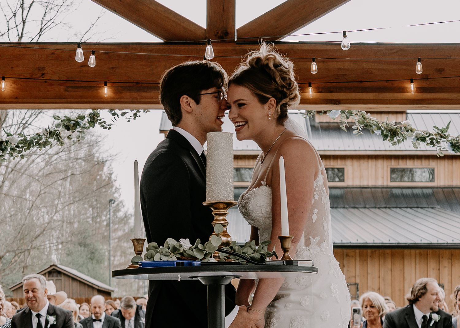 Intimate moment between bride and groom during wedding reception at rustic venue.