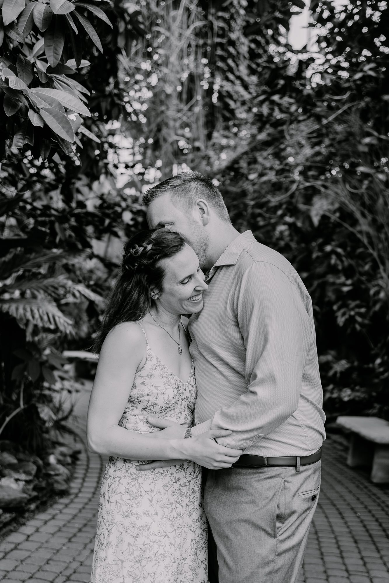 Black and white intimate portrait of a couple embracing on a garden path.