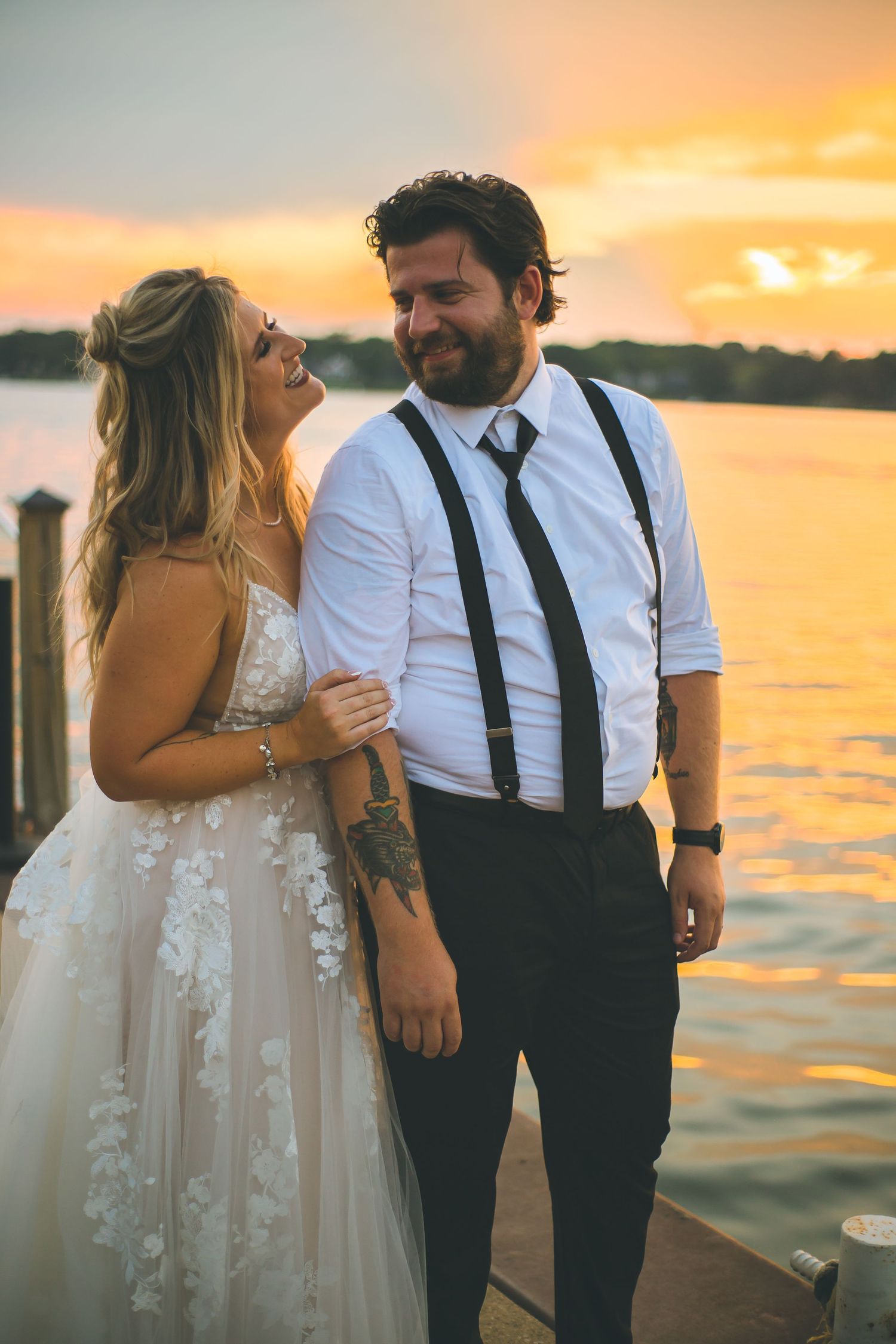 Romantic sunset wedding photos by the water with golden light illuminating the couple.