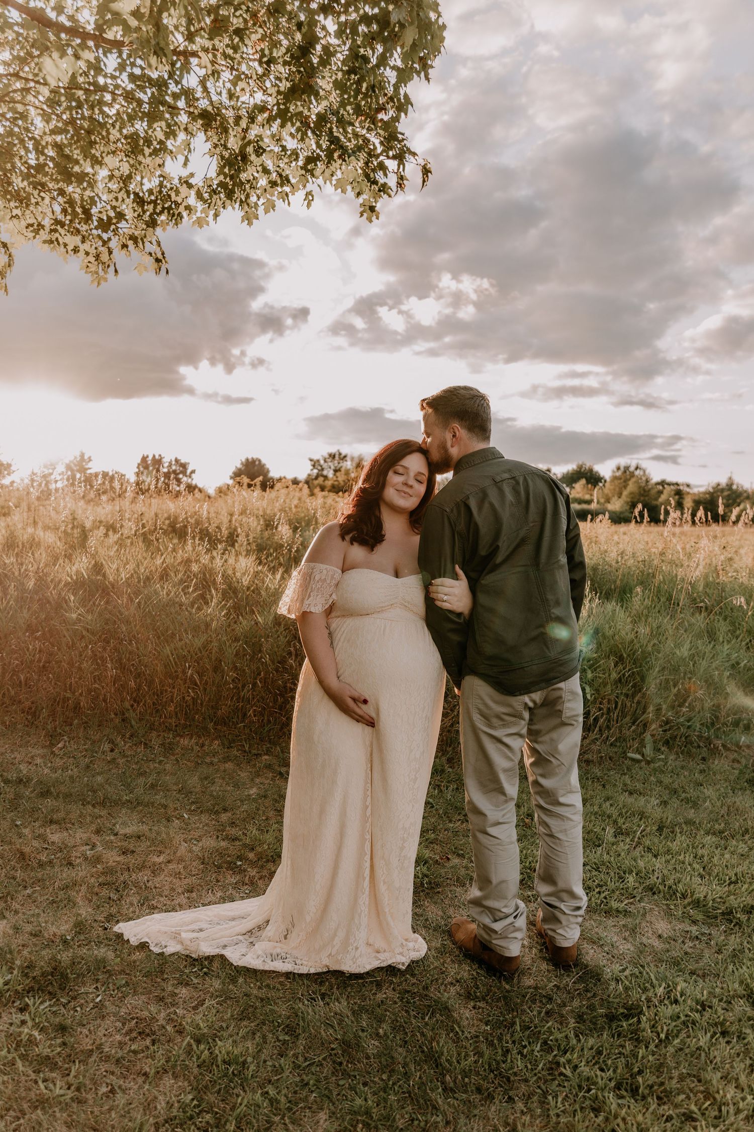 Maternity portraits capture tender moments between a couple in a rustic outdoor setting at sunset.