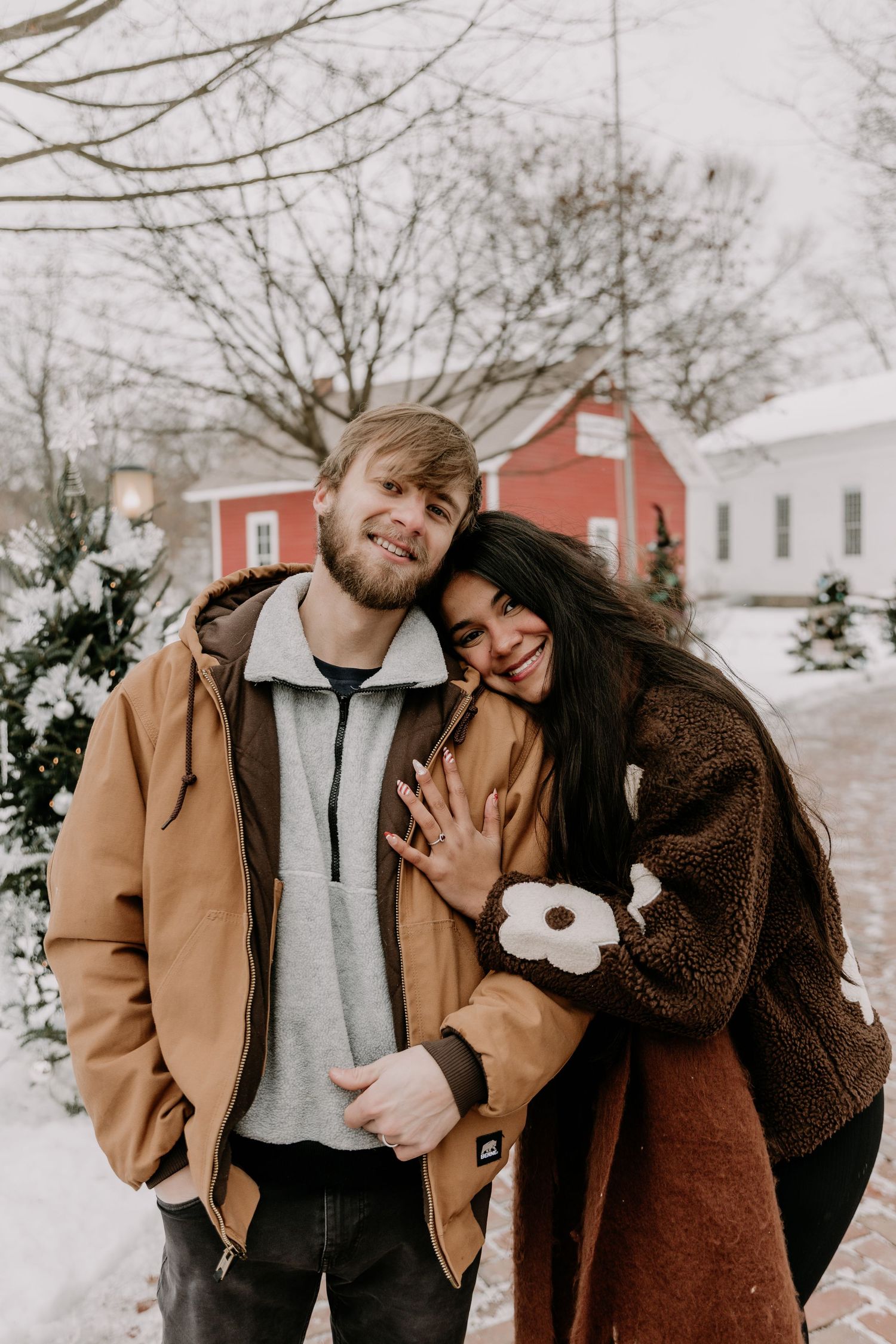 A couple shares tender moments in a snowy winter setting while wearing cozy outerwear and embracing each other.