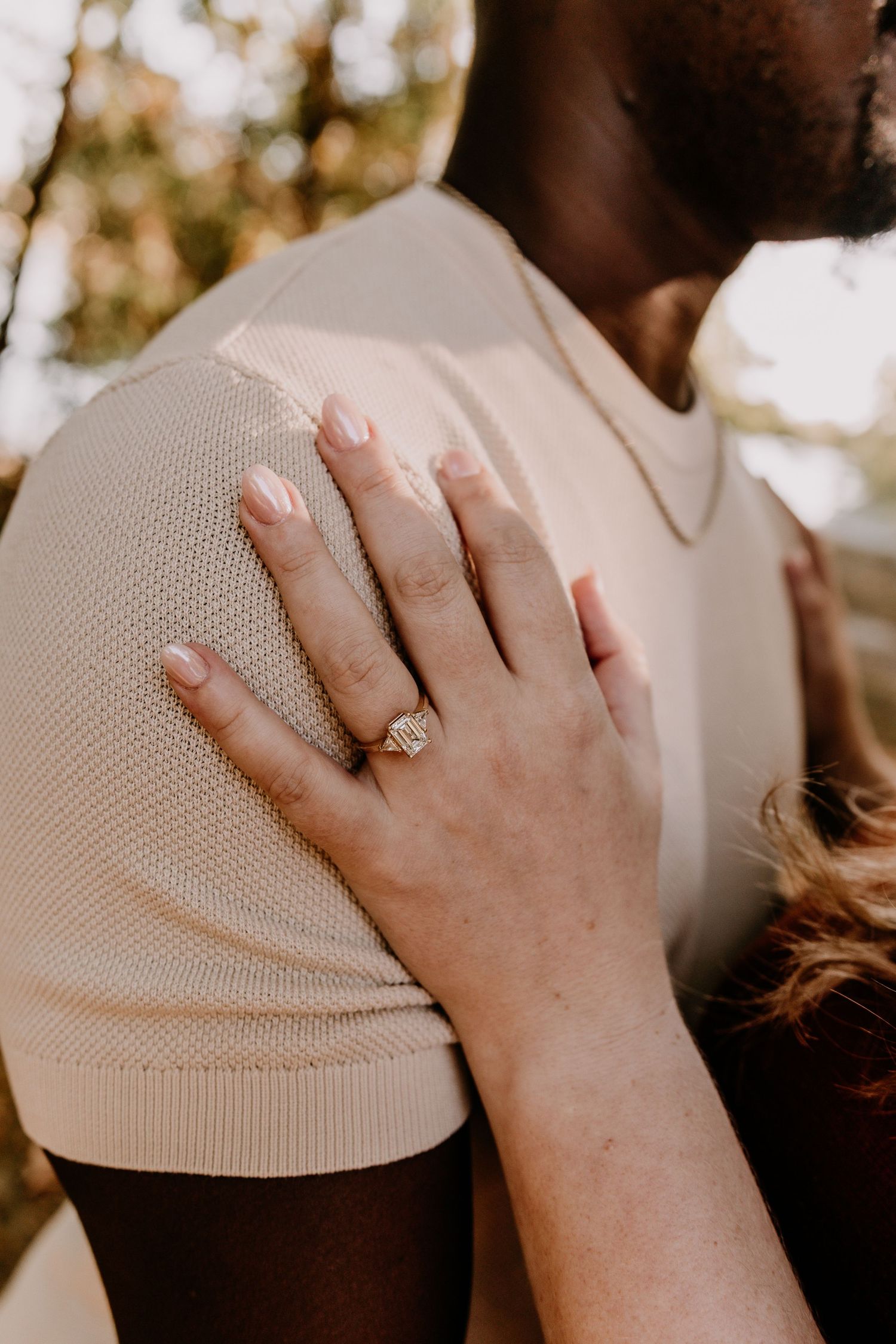Close-up sequence showing a hand wearing an engagement ring placed on someone's head in a tender gesture.