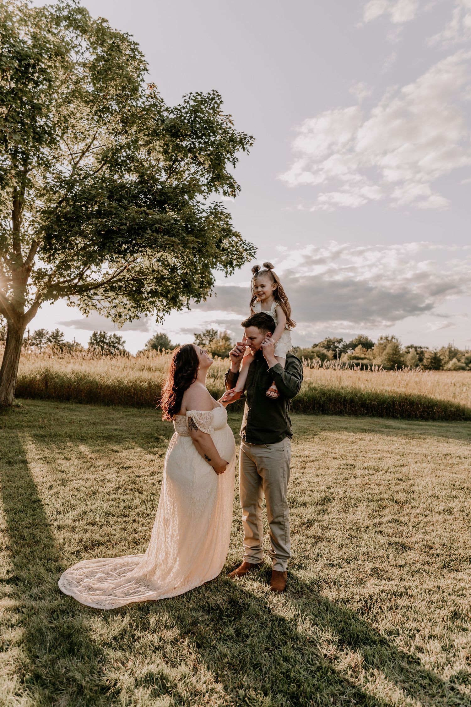A couple dances together in an open field during a sunset photo session with flowing dress movement.