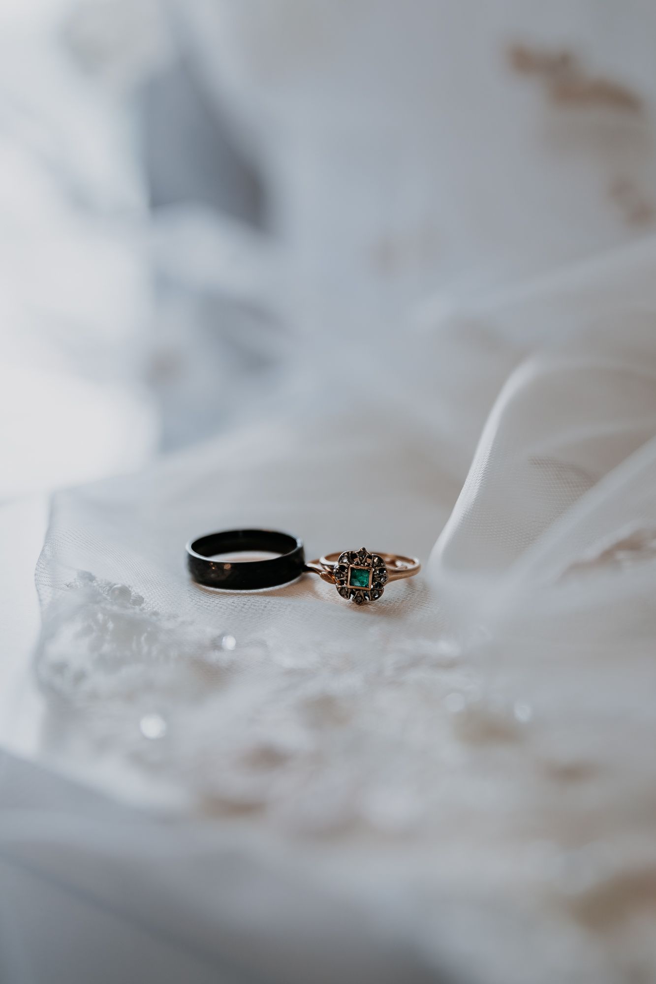 Wedding rings resting on delicate white lace fabric in soft focus.