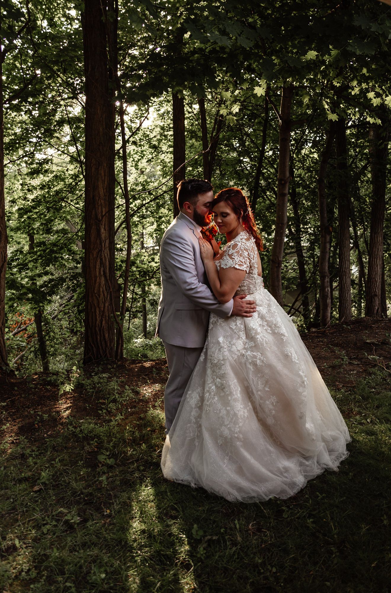 Wedding photography in a wooded setting with natural sunlight filtering through the trees.