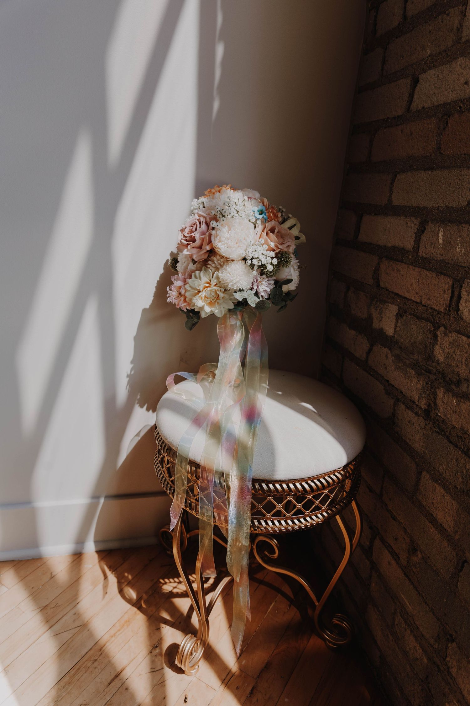 Floral crown with white and pink blooms sits on vintage chair in dramatic lighting.