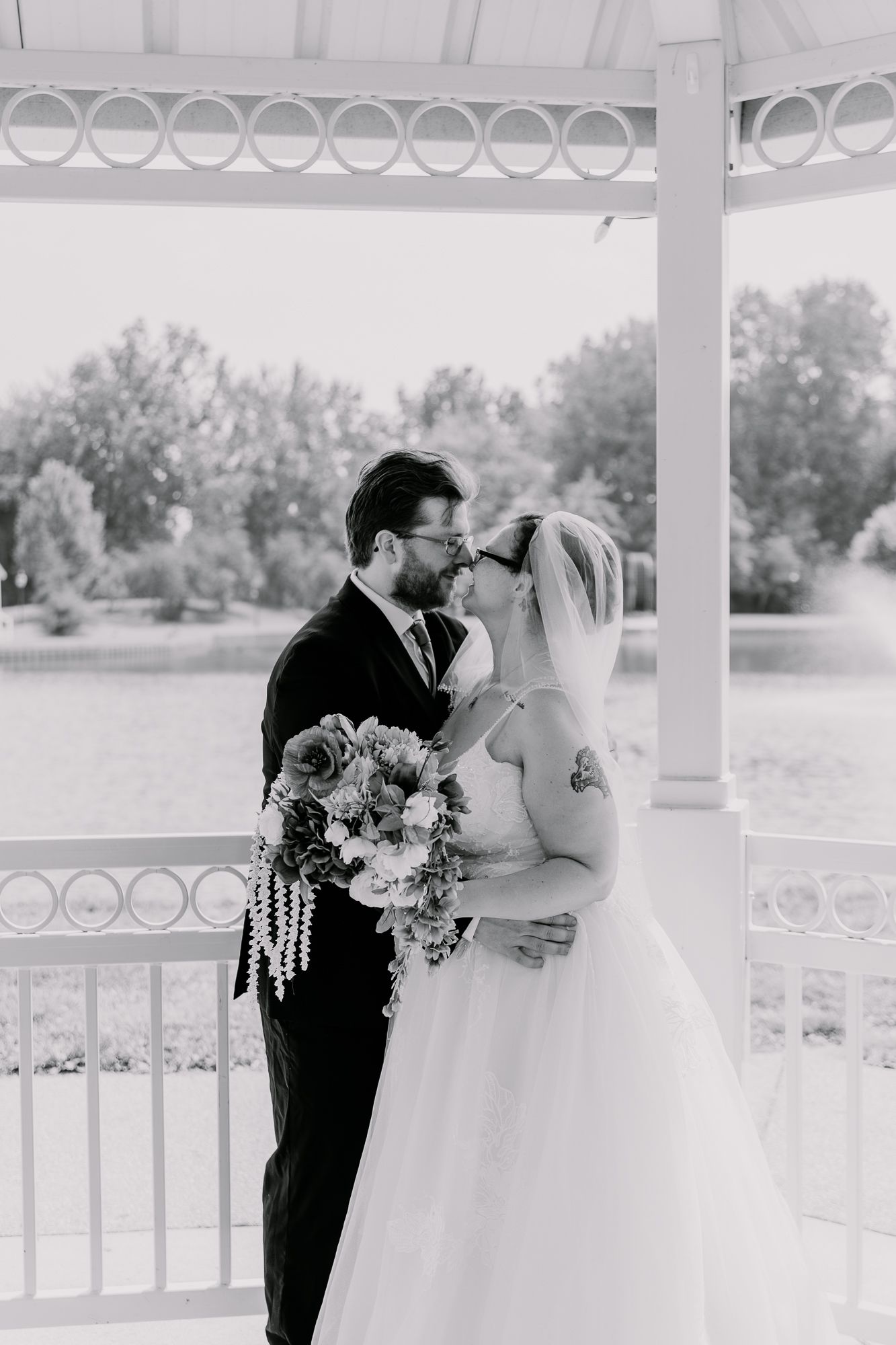 Romantic couple shares intimate moment under white gazebo during wedding.