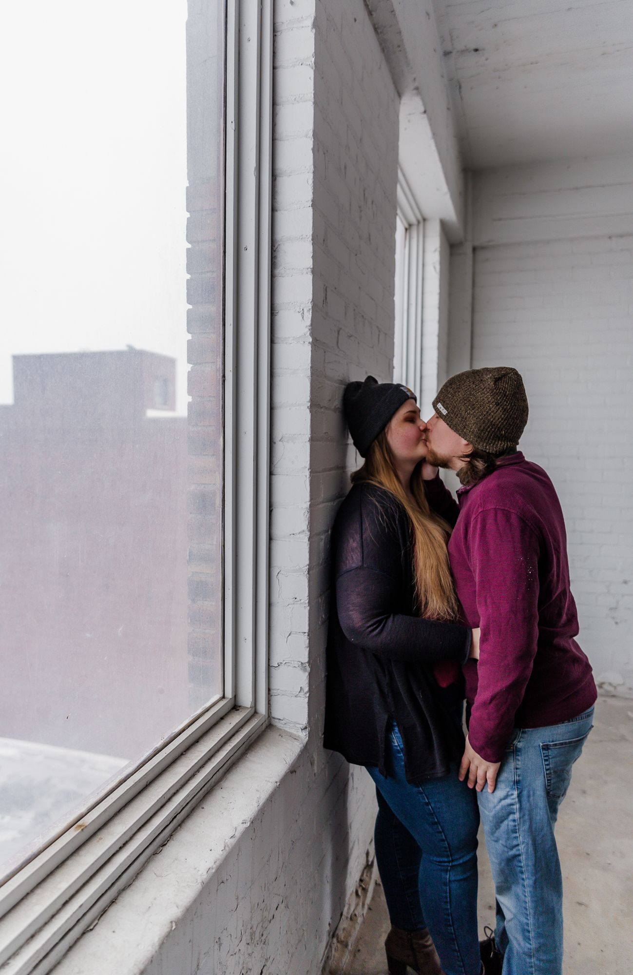 Couple sharing tender moments by a bright window in an indoor setting.