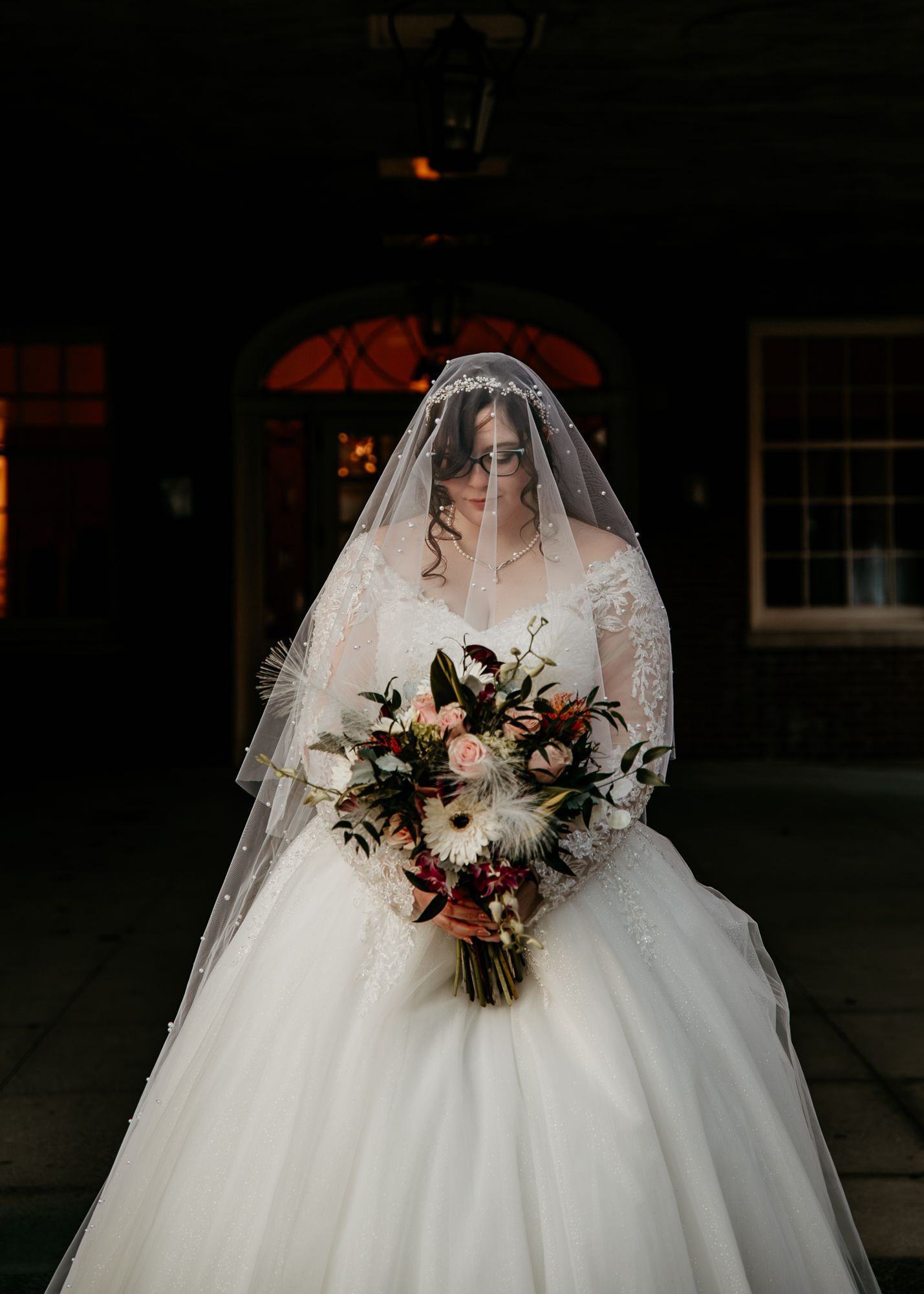 Wedding dress and bouquet silhouetted in dramatic low-light photography.