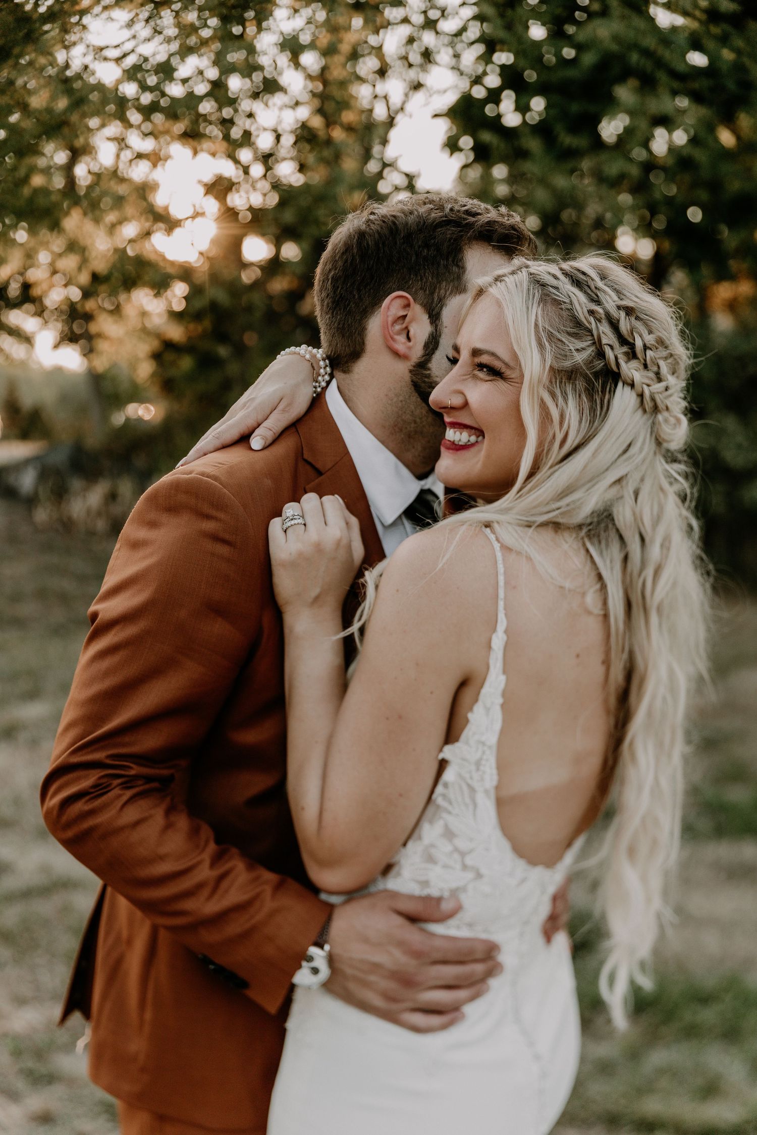 Couple sharing intimate moments against scenic outdoor backdrop at sunset in rustic wedding attire.