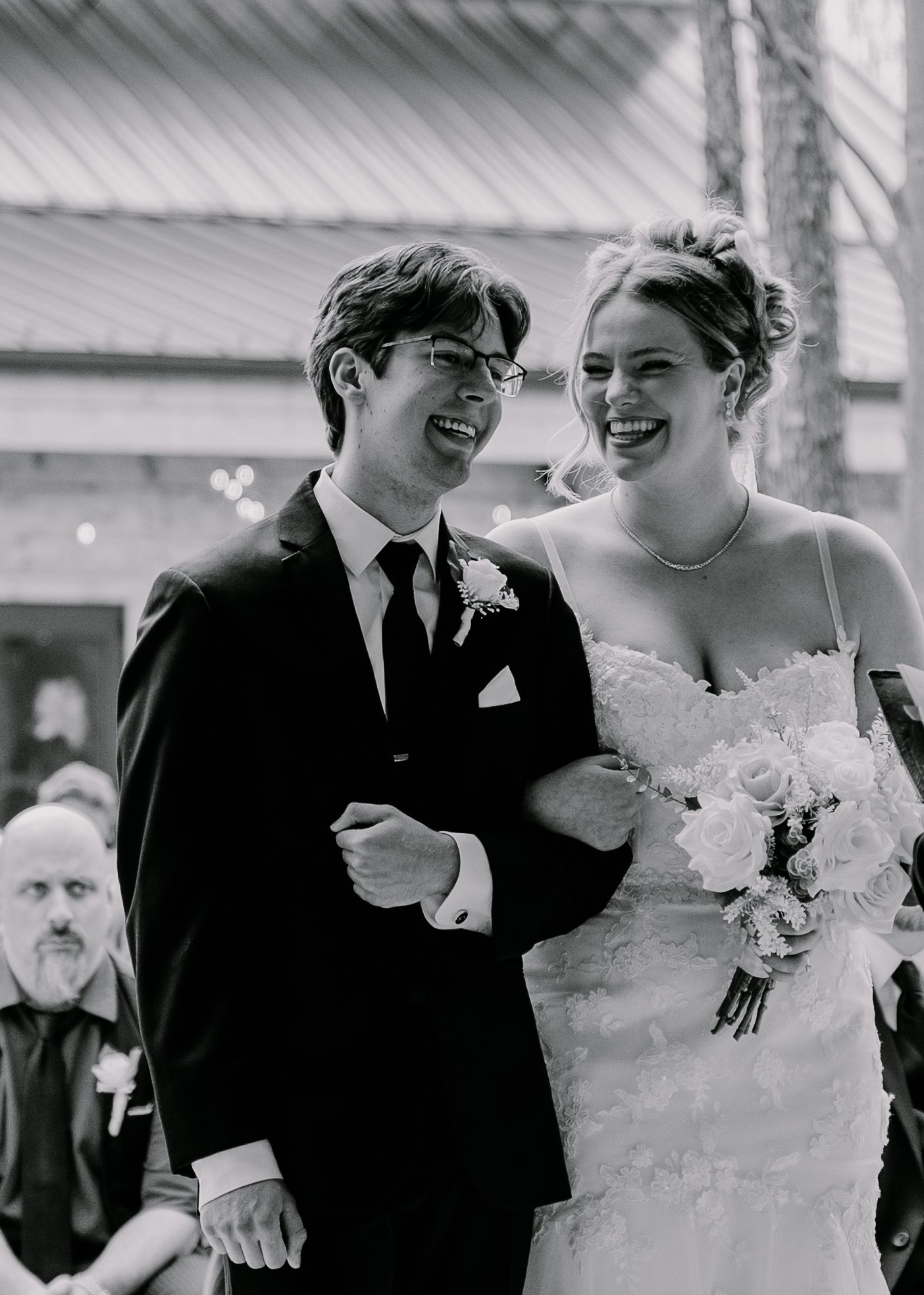 Black and white photo of newlyweds laughing together during wedding ceremony.
