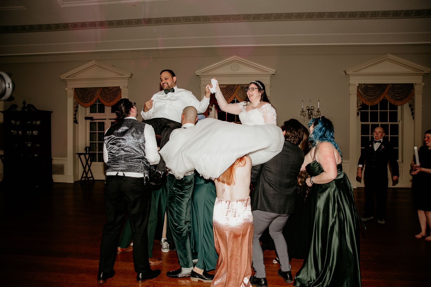 Lively wedding reception showing guests dancing and celebrating in formal attire.