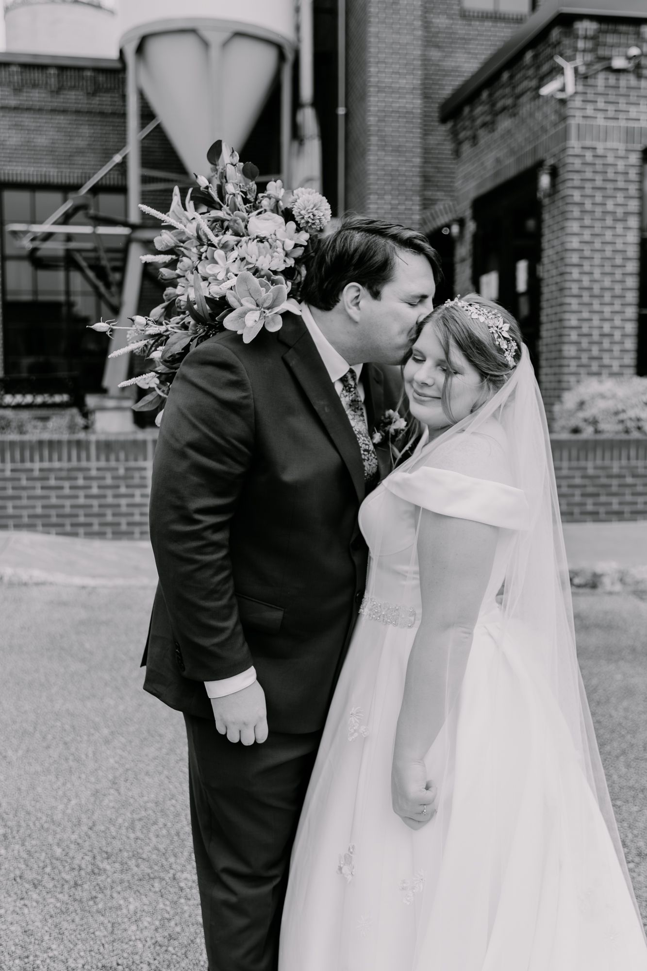Bride and groom share intimate moment during wedding photoshoot at industrial venue.