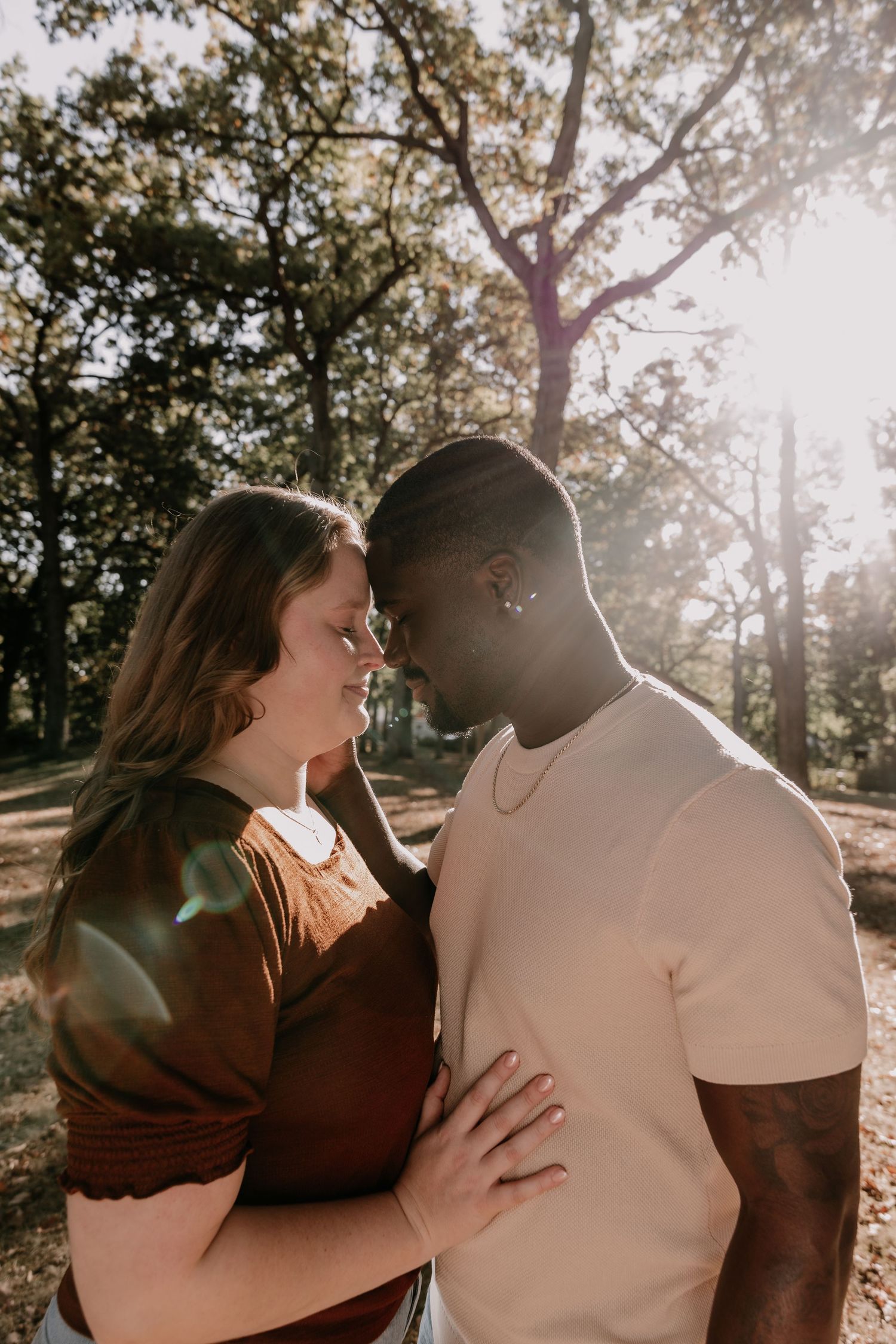 A couple shares intimate moments in a sunlit outdoor setting during a romantic photoshoot session.