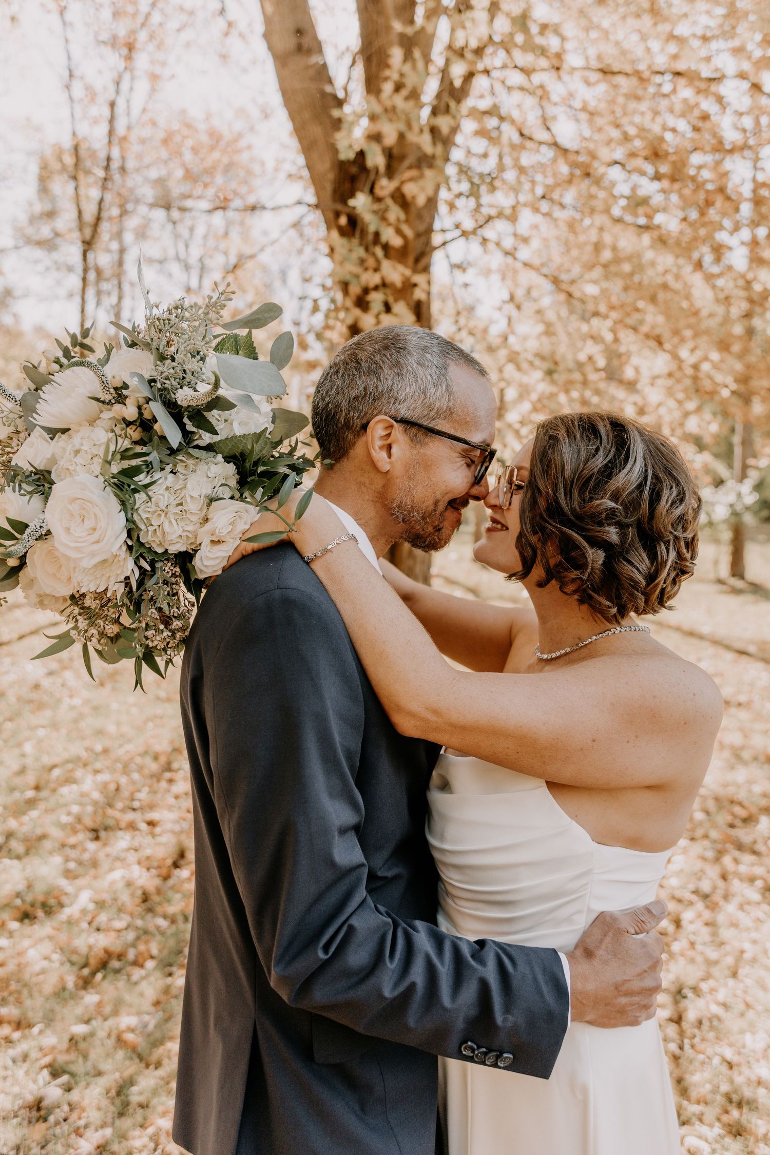 A romantic autumn wedding moment captured in a series of four intimate photos with warm fall foliage in the background.