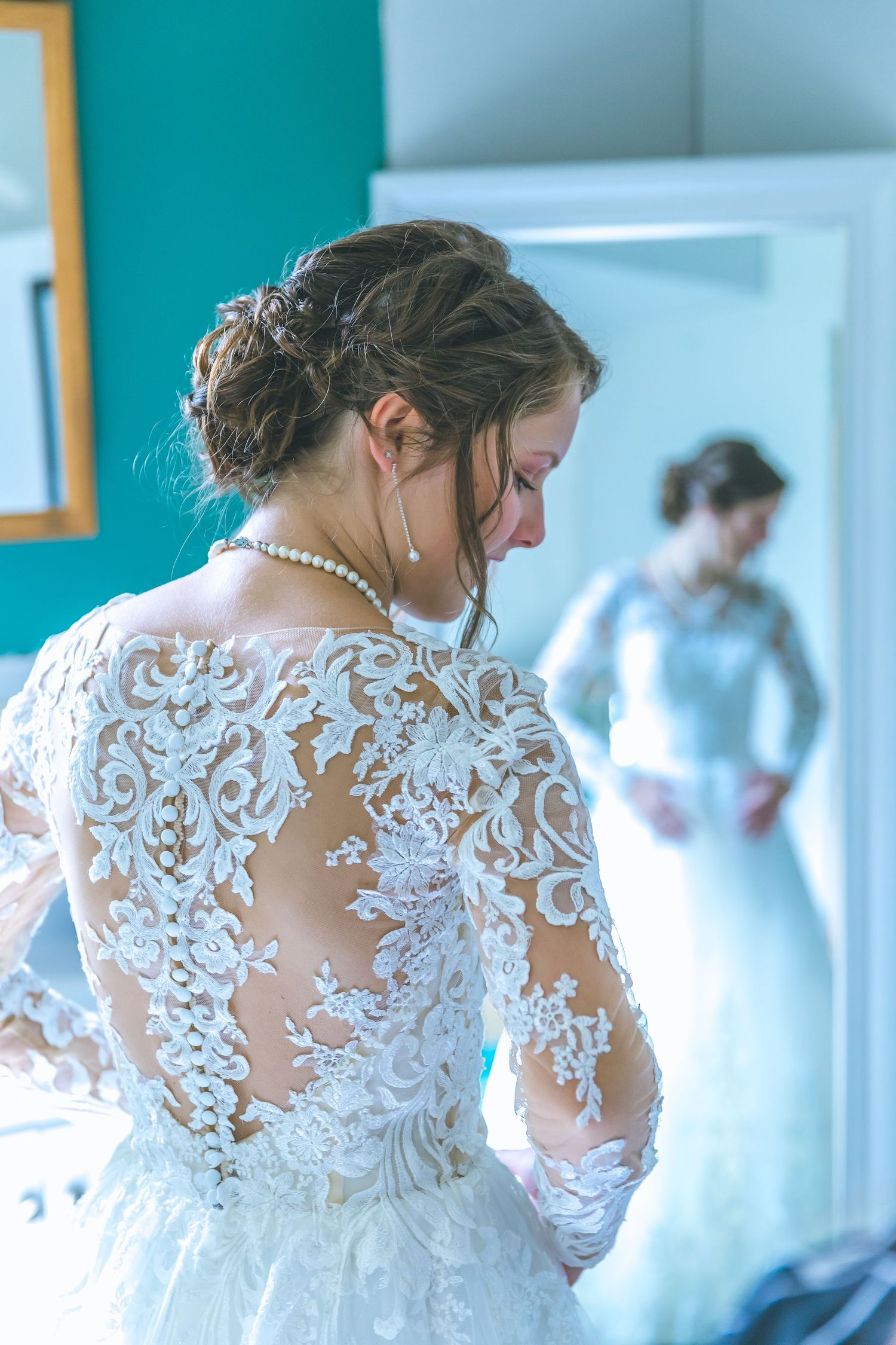 Delicate lace details of a wedding dress shown in soft, dreamy lighting.