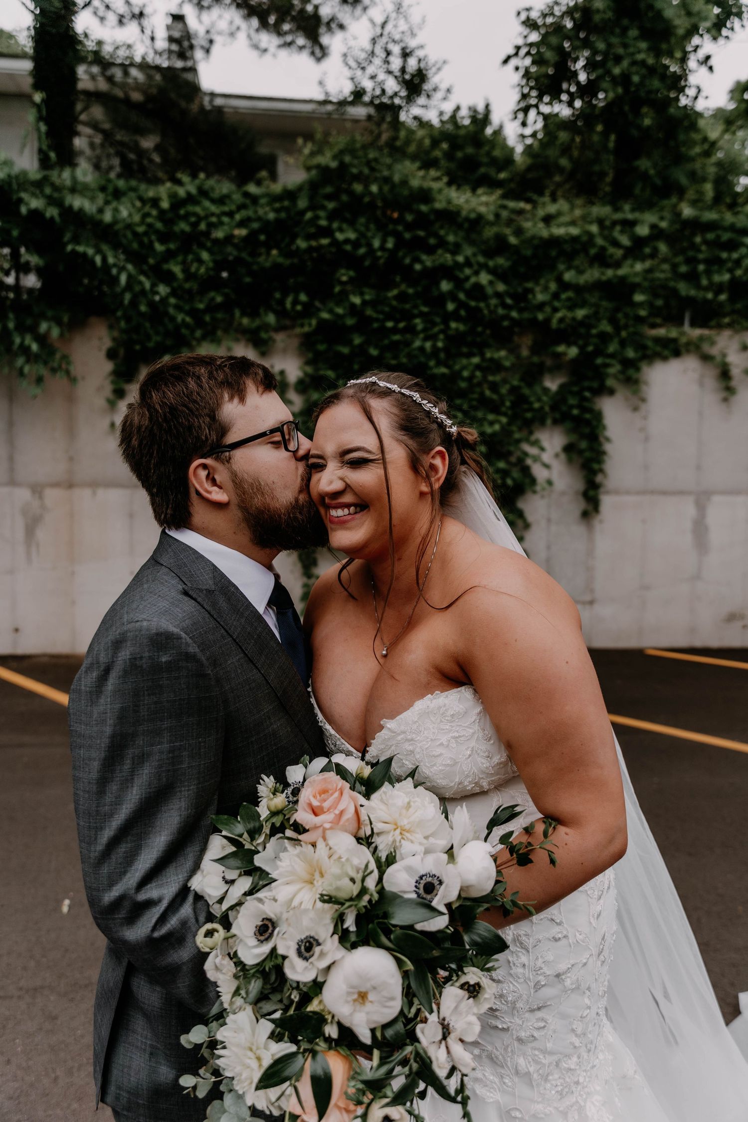 Joyful wedding couple embraces while holding elegant white and pink floral bouquet.