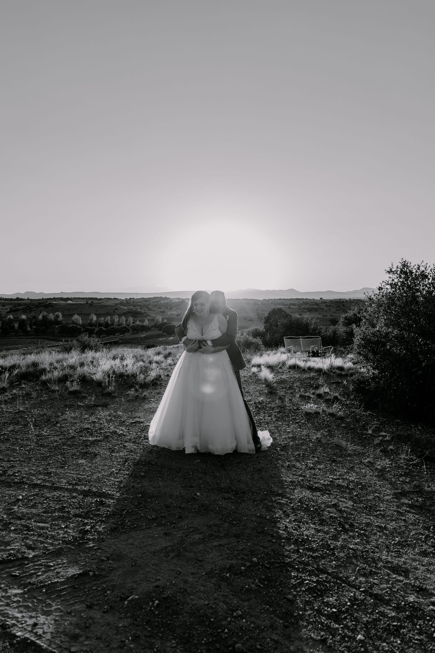 Black and white desert wedding photo with dramatic backlighting and mountain views.