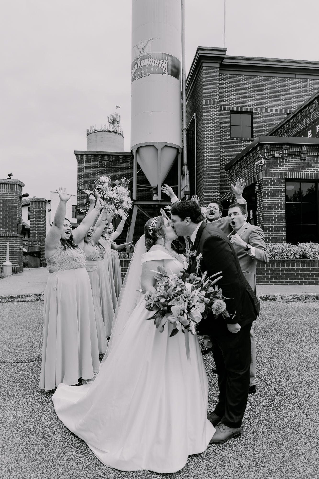 Wedding party arranges for formal portraits outside brick venue with elegant styling.
