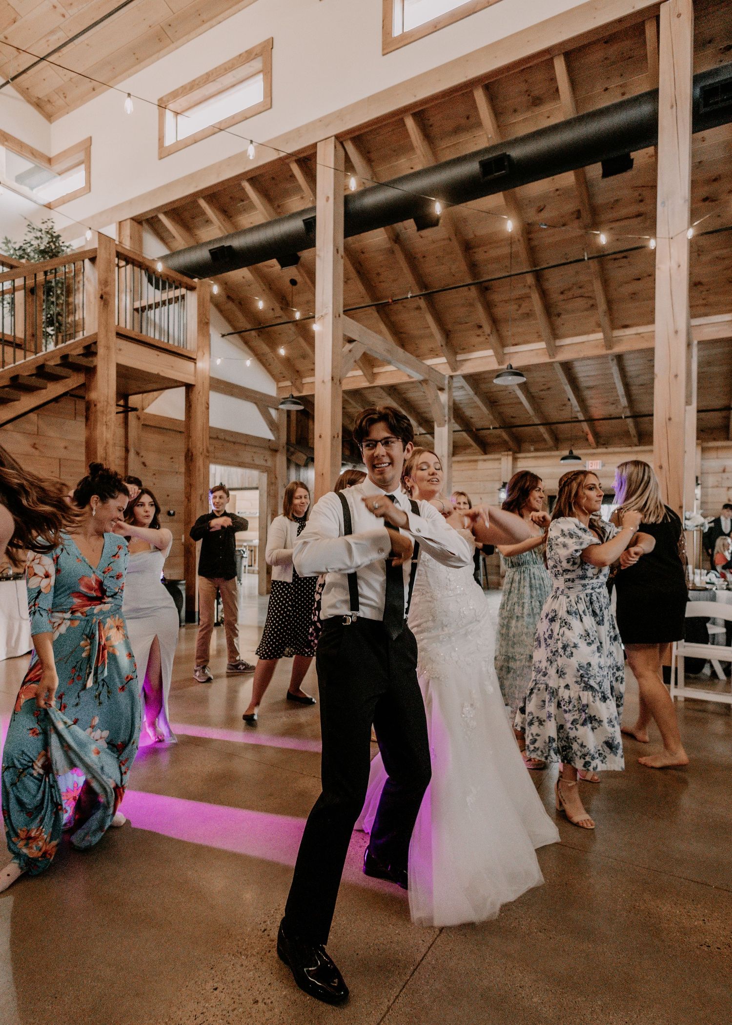 Wedding reception dancers celebrating on the dance floor with purple accent lighting.