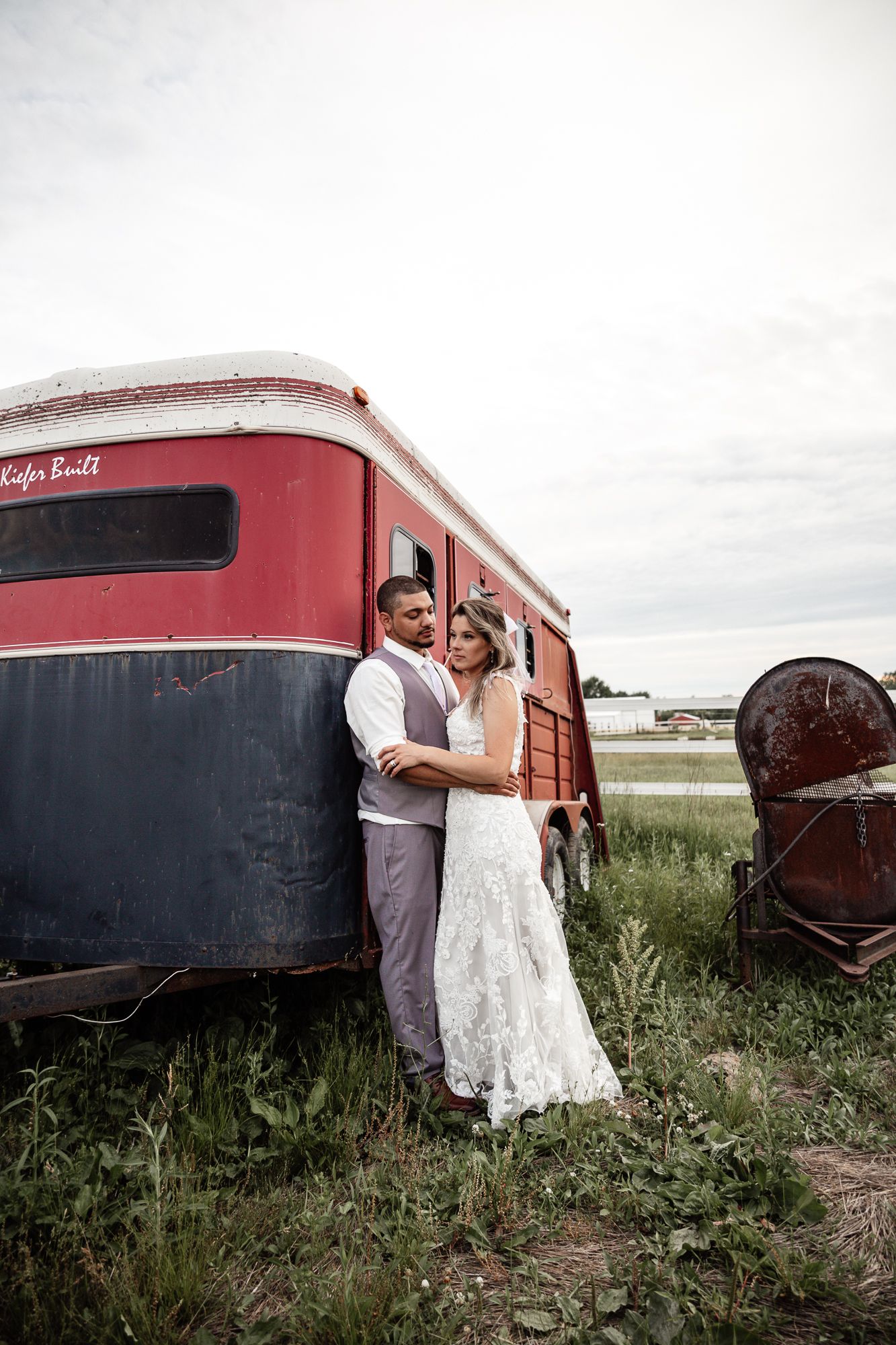 Wedding portraits taken against a vintage red and black train car in rustic setting.
