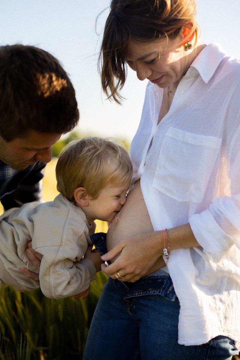 Family shares intimate moment in wheat field at sunset.