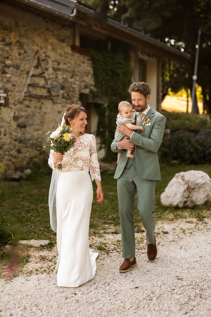 Wedding couple walking on stone path near rustic building.