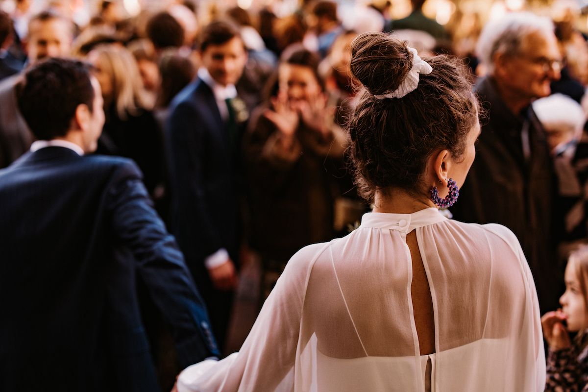 Back view of wedding guest watching crowd at outdoor ceremony.