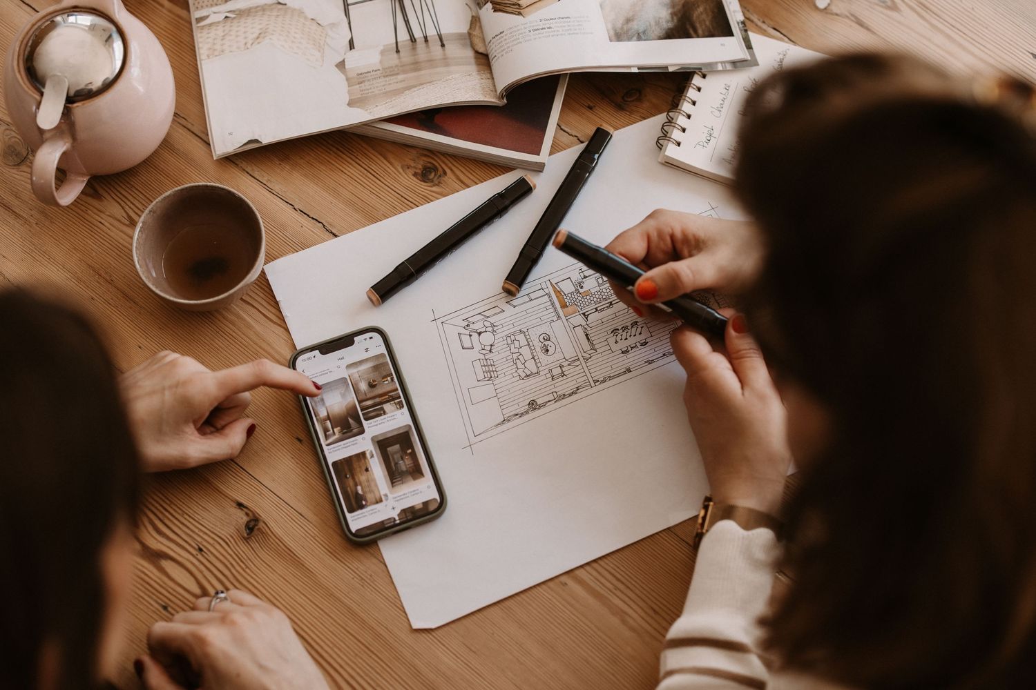 Sketching and planning materials laid out on a wooden desk surface.