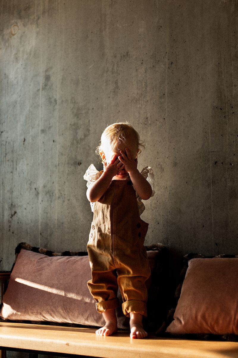 Sequence of shadowy figures sitting on a couch against a concrete wall in dramatic lighting.