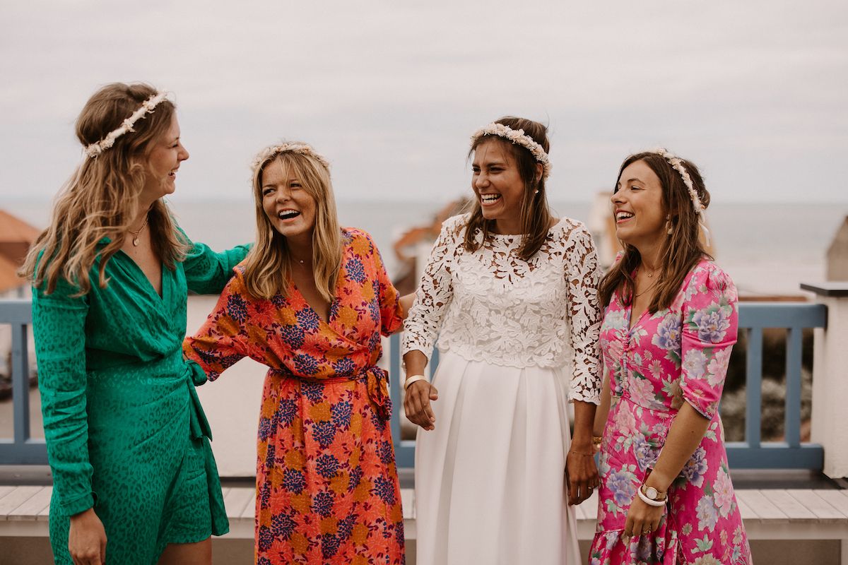A group of wedding guests in colorful dresses celebrate together on a balcony.