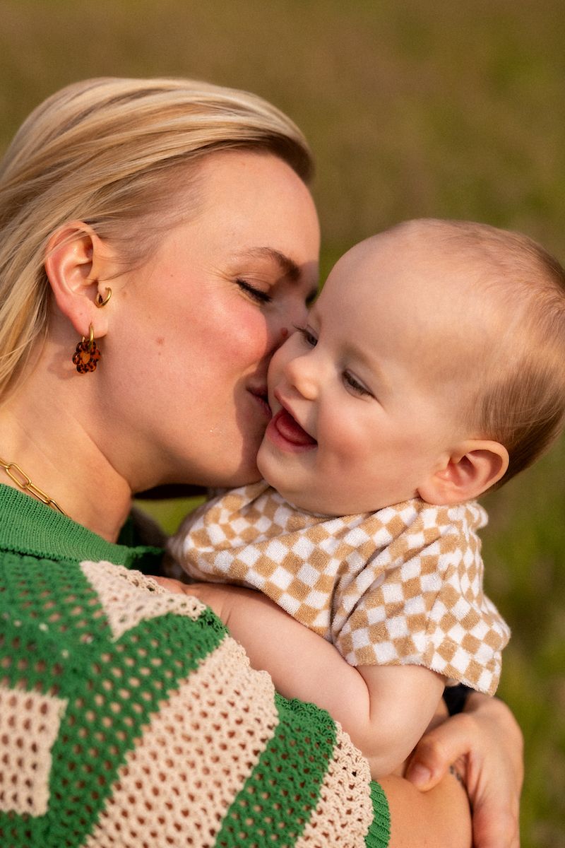 Tender moment captured between loved ones wearing polka dot patterns in natural outdoor setting.