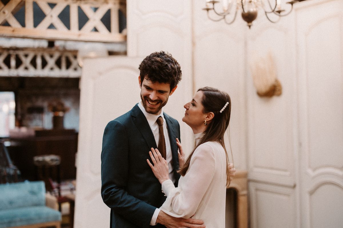 Romantic indoor portrait of formally dressed couple sharing intimate moment in elegant setting.