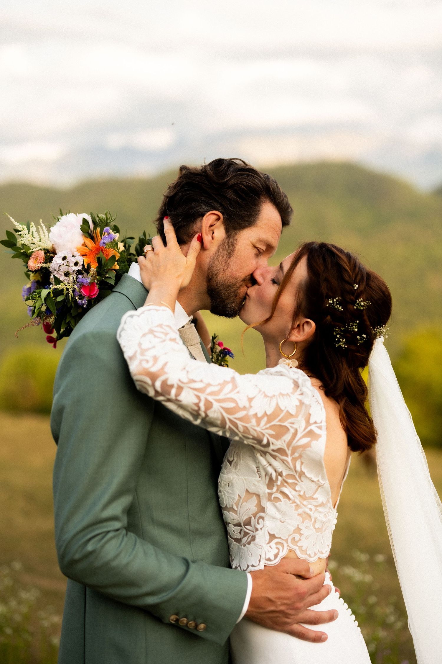 Romantic wedding portrait of couple kissing against mountain landscape.