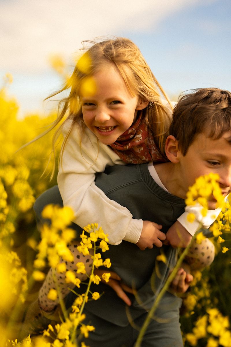 Playful moments captured in blooming yellow canola field during golden hour.