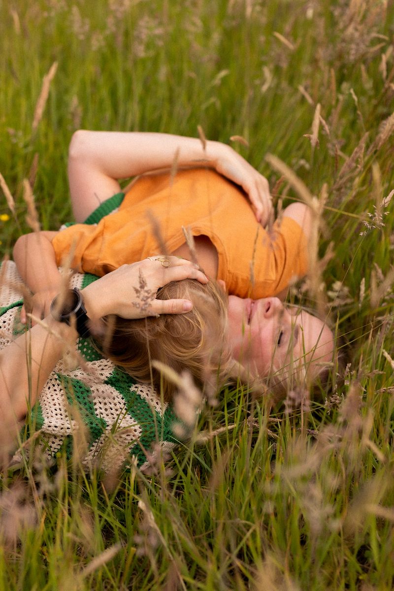 Peaceful moment lying among tall grass and wildflowers on summer day.
