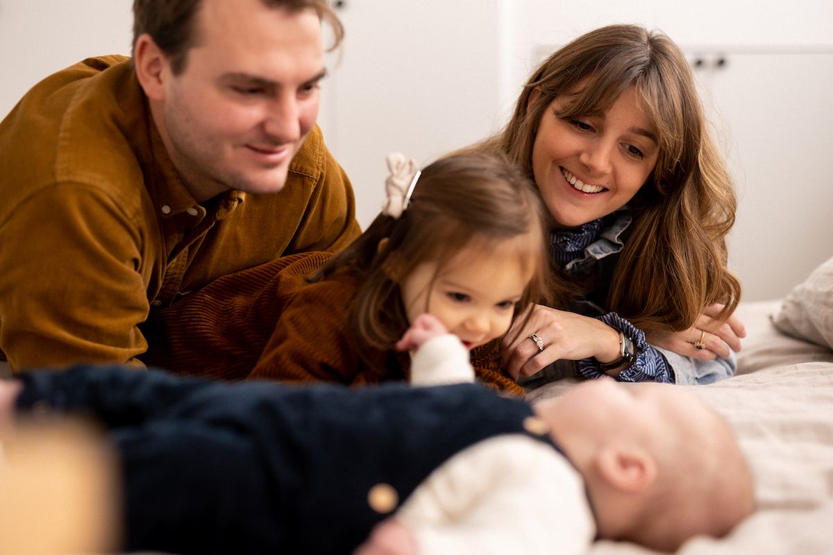 A family shares an intimate moment together while relaxing on a bed.