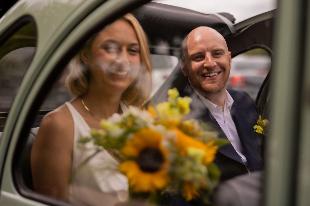 Candid moments captured through car window during wedding celebration.