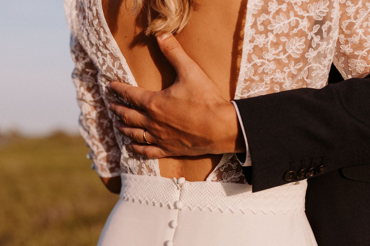 Close-up detail of a white lace wedding dress with delicate buttons down the back.