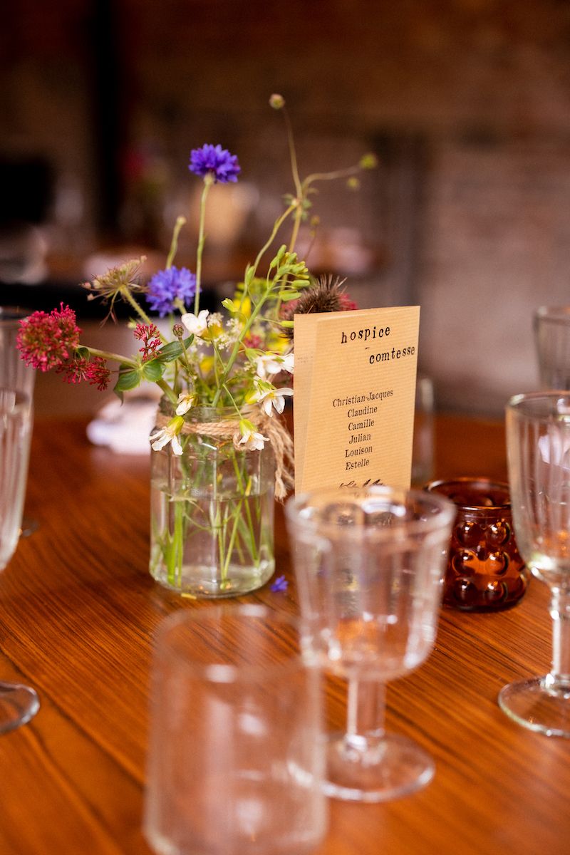 A rustic table setting with wildflowers in a mason jar and a menu card.