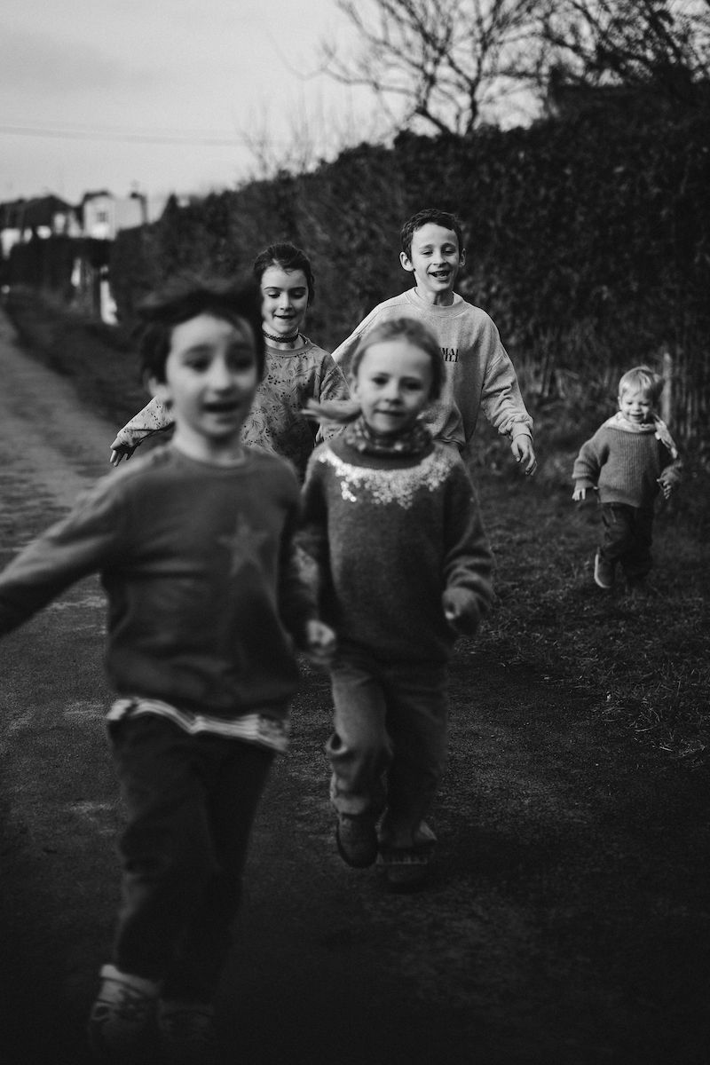 Black and white image of children running and playing on a path outdoors.