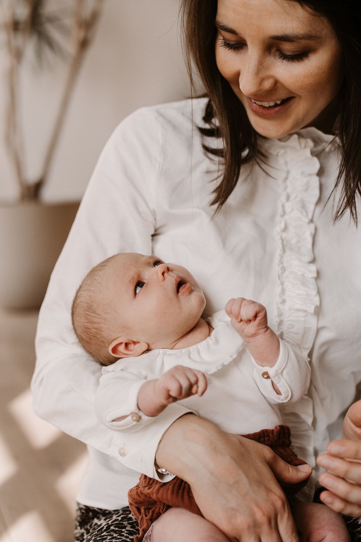 Baby and parent sharing intimate moment in white clothing.