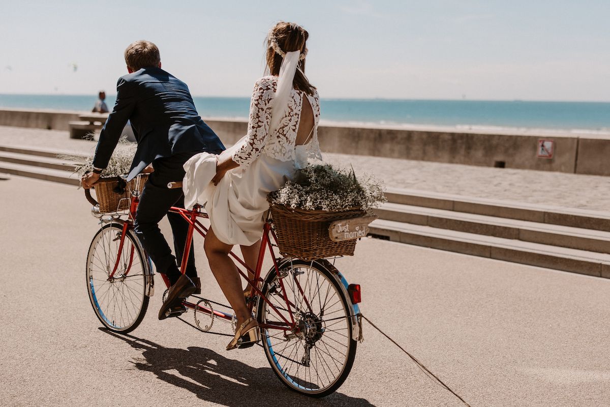 Couple riding bicycles along sunny seaside promenade.