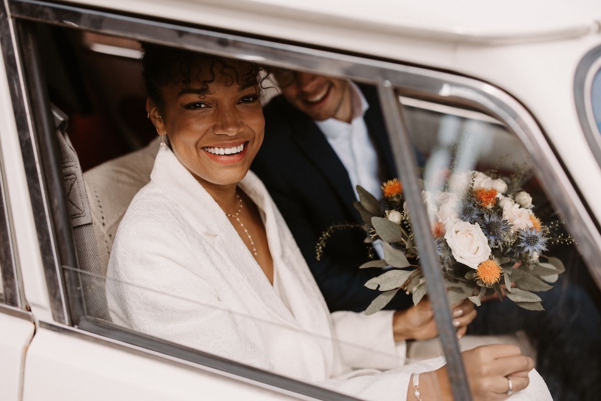 Classic wedding car scene with joyful newlyweds.