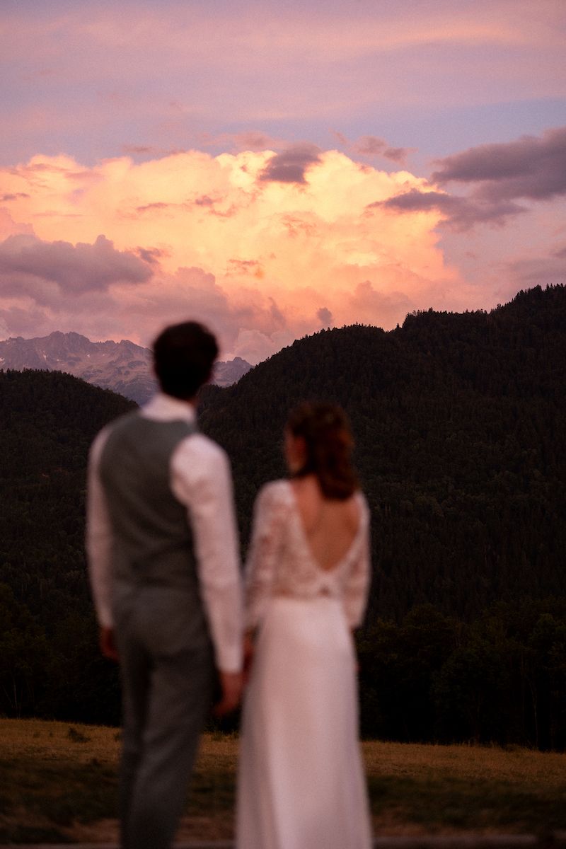 Silhouette of a couple watching a dramatic sunset over mountain peaks.