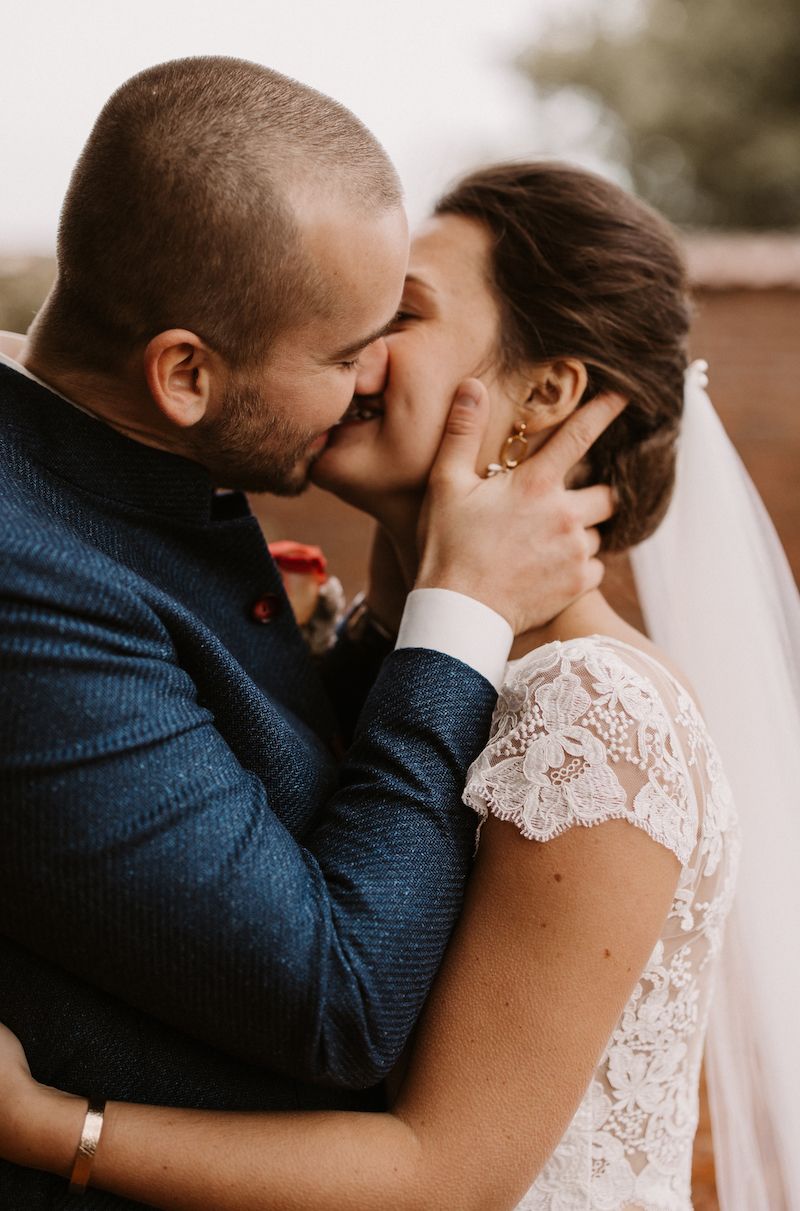 An intimate wedding portrait showing tender moment between couple in blue suit and lace dress.