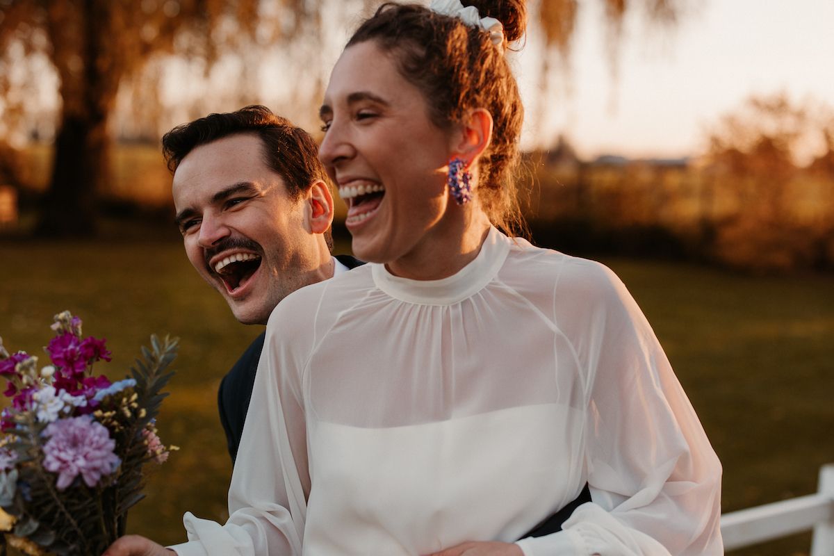 Joyful moment captured during sunset with white dress and floral bouquet.