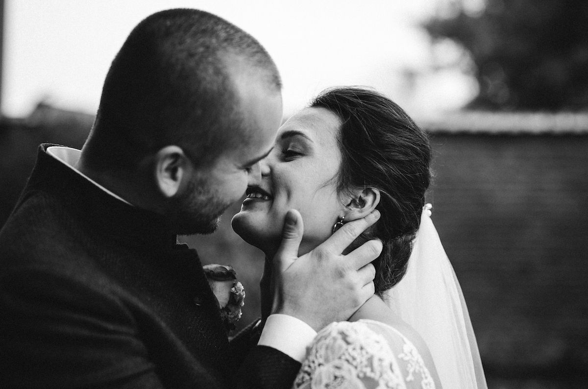 A black and white candid wedding photo capturing an intimate moment between newlyweds.