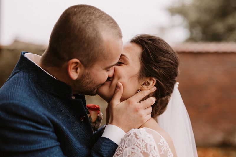 Intimate wedding moment captured against brick wall with soft lighting.