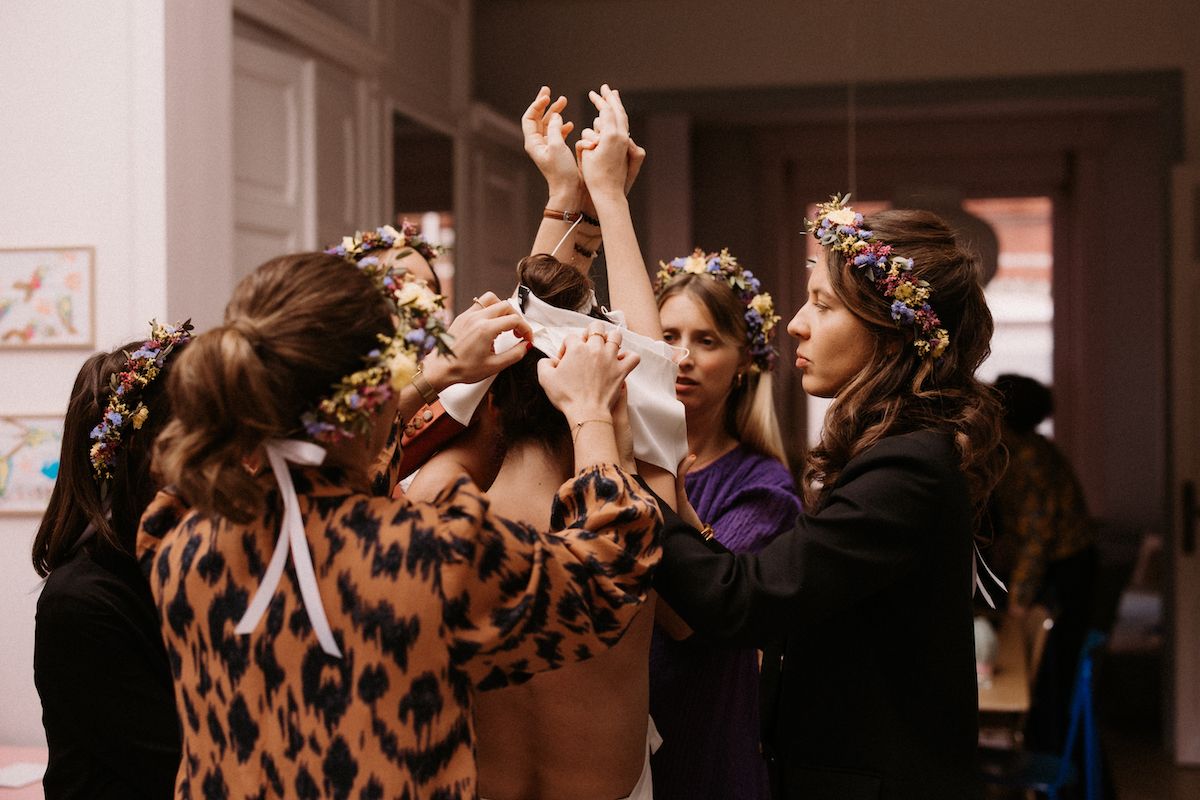 Wedding party raising hands together in celebration indoors.